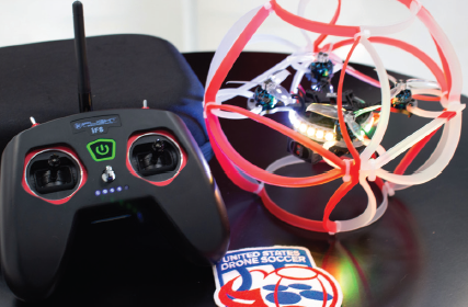 A drone soccer ball sits next to a drone soccer transmitter.